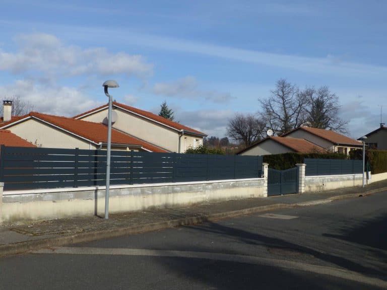 Clôture en aluminium à lames posée sur un muret le long de la rue, en rénovation à Limas